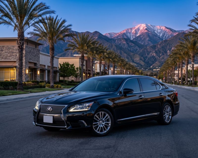 Lexus Sedan on a palm-lined boulevard below a snow-capped mountain at blue hour