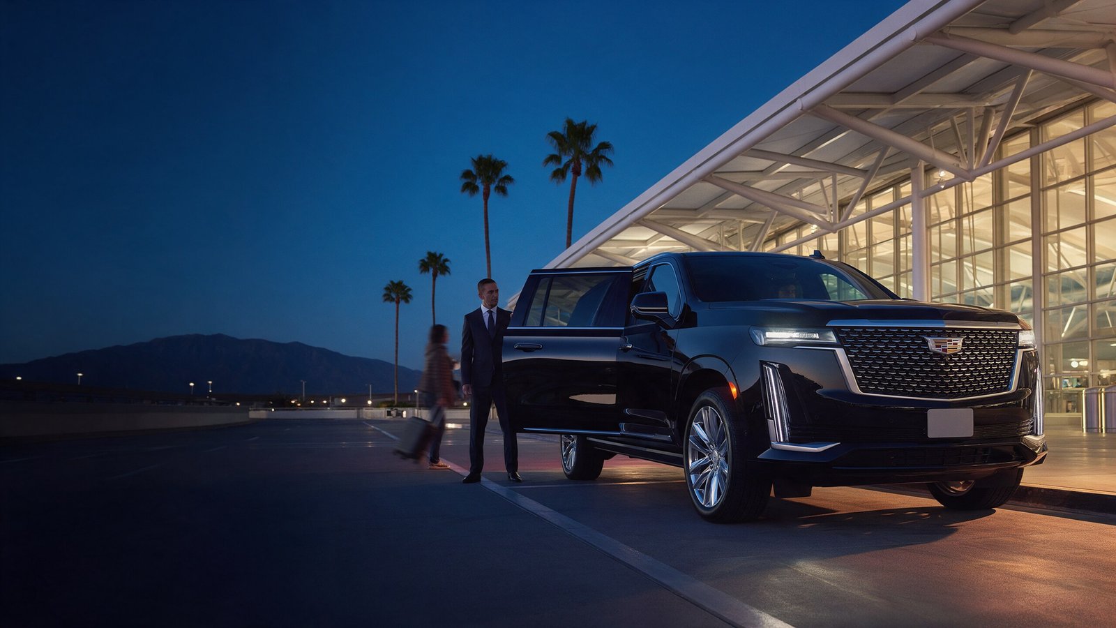 Low-angle view of the Black Cadillac Escalade at an airport terminal curb at dusk